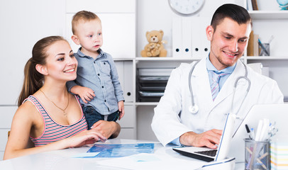 Man medical worker talking with young mother