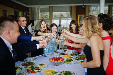 Group of graduates clinking and celebrating in the restaurant the end of their studying in the university.