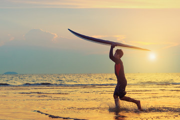 Man running with surfboard on the beach.