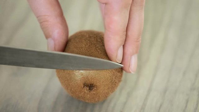 Slicing orgenic kiwi on wood cutting board