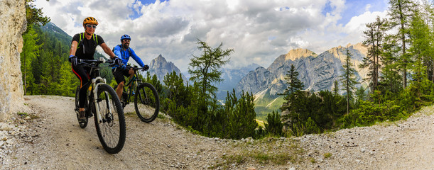 Mountain biking couple with bikes on track, Cortina d'Ampezzo, Dolomites, Italy