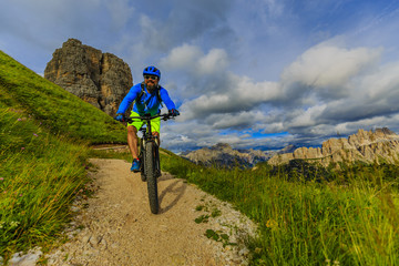 Fototapeta premium View of cyclist riding mountain bike on single trail in Dolomites, Cinque Torri, South Tirol, Italy