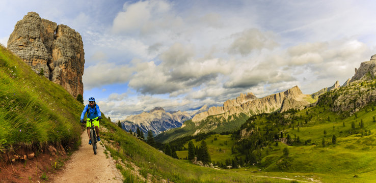 View of cyclist riding mountain bike on single trail in Dolomites, Cinque Torri, South Tirol, Italy