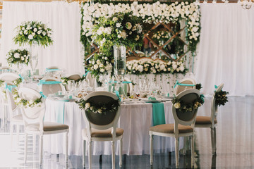 Dinner tables with mint clothes decorated with white roses
