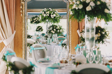 Mirror reflects vase with white roses on a dinner table