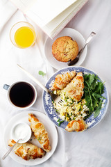 Breakfast in bed. Scrambled eggs with cheese croissants, raspberry muffin and black coffee. Morning treat concept. Composition with copy space.