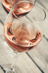 Two glasses of rose wine on wooden table, shallow DOF