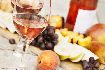 Two glasses of rose wine and board with fruits, bread and cheese on wooden table - 166305125