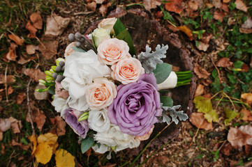 Obraz na płótnie Canvas Close-up photo of an incredible wedding bouquet laying on the stump. Fallen leaves on the background.
