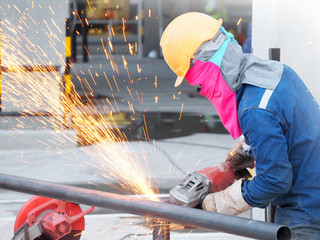 Worker grinds the steel of angular grinding machine