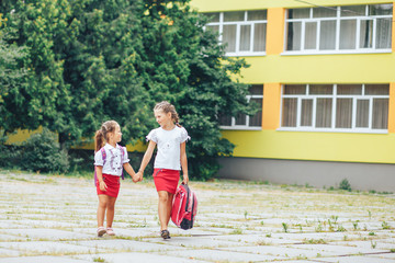 Fototapeta na wymiar Two cute girls go to school holding hands