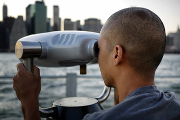 Fototapeta na wymiar Man looking through telescope towards New York City's financial district