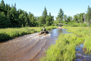 Three men driving ATV quad through dirty water in forest © Drepicter
