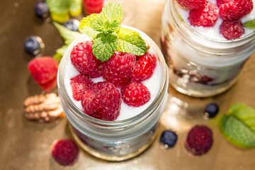Healthy breakfast - dessert with yogurt, granola, outs flakes, jam, raspberries, blueberries, hazelnut and mint
