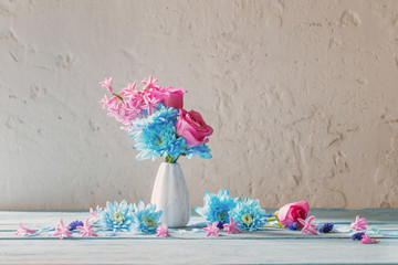 blue and pink flowers in vase on white grunge background