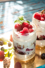 Healthy breakfast - dessert with yogurt, granola, outs flakes, jam, raspberries, blueberries, hazelnut and mint