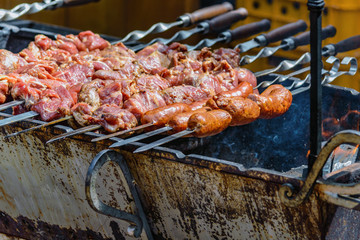 cooking meat and sausages on skewers, shashlik on coals