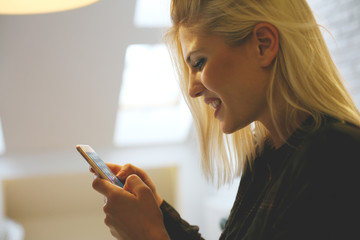 Smiling Caucasian woman typing message on smart phone.