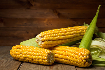 Ripe yellow sweet corn cob on a wooden table close-up