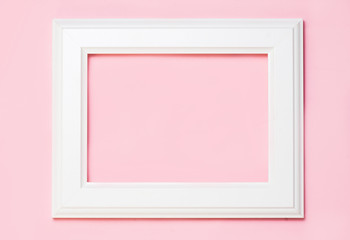 White wooden frame on pink background, free space for your text. top view, flat lay