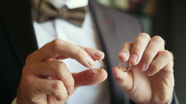 Groom holds golden wedding rings in hands - wedding concept