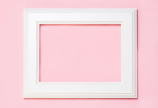 White wooden frame on pink background, free space for your text. top view, flat lay