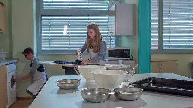 A girl is ironing some shirts on an ironing board in her home economics clas.
