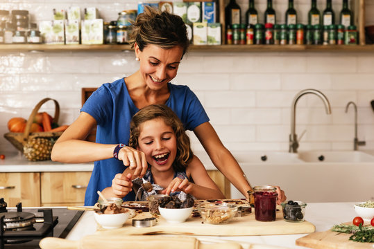 Little Girl Cooking With Her Mother In The Kitchen.