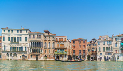 Venetian landscape with typical buildings, Grand canal and gondola at noon time.