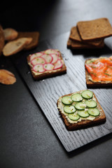 Obraz na płótnie Canvas Sandwich with cereals bread smoked salmon beetroot and cucumber on dark marble background