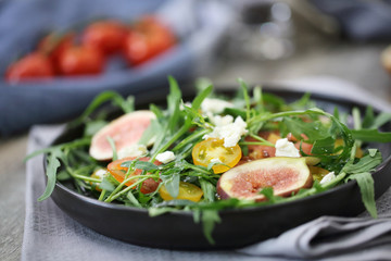 Fresh salad with arugula tomato and cheese on wooden background