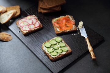 Sandwich with cereals bread smoked salmon beetroot and cucumber on dark marble background