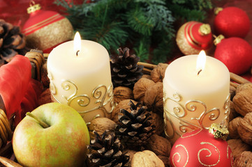 Christmas decoration of burning cancles,baubles and pine cone and apple