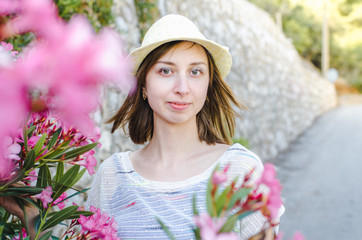 Young beautiful smiling woman in a hat looks at the camera on the background of a griffin wall and flowers
