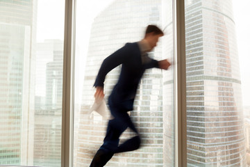 Busy businessman hurrying up to come at meeting on time in office building, blurred silhouette...