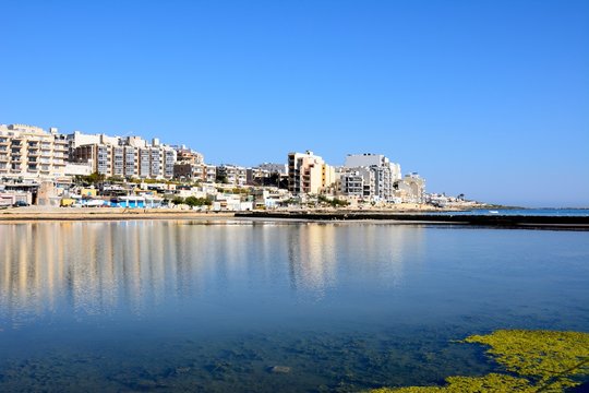 View of salt pans with buildings to the rear in Salina Bay, Bugibba, Malta.
