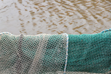 Fischernetz hängt über der Reling mit Blick auf das Wasser