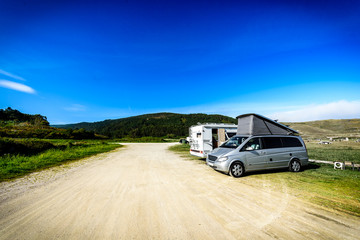 Motorhome RV and campervan are parked on a beach.
