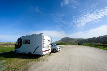 Motorhome RV and campervan are parked on a beach.