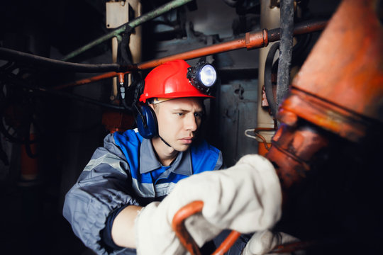 young coal miner is underground in a mine for coal mining in overalls against the backdrop of mining equipment. concept of repair of industrial equipment.