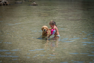 kid girl washing the dog in the sea
