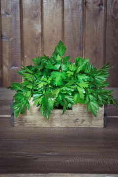 Fresh green parsley in wooden box on the old wooden table, selective focus.