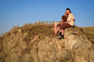 Naklejka na ściany i meble Couple in love sitting, hugging and enjoying on the top of the mountain in the sunset