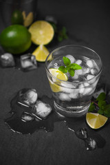 Mojito cocktail with lime and mint in glass on a grey stone background