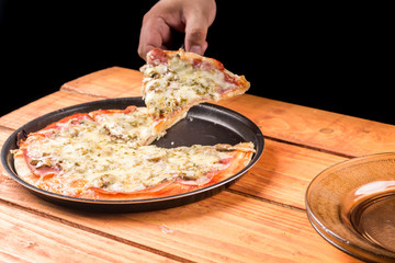 Slicing fresh baked pizza with mushrooms ham cheese on the wooden board table