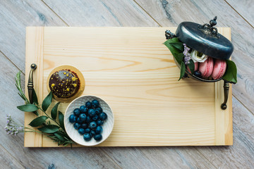 Pastries, macaroons and berries on a wooden background