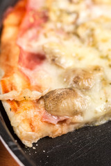 Sliced fresh baked pizza with mushrooms cheese ham ketchup on the round baking pan