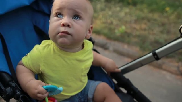 Curious infant boy sitting in pram outdoors