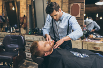 barber trimming customers beard