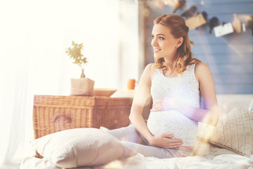 Cheerful pregnant woman resting in bed